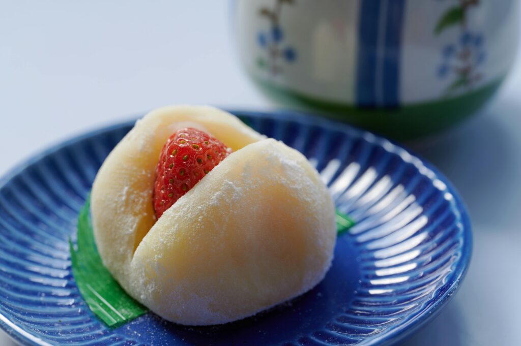 Close-up of a sweet strawberry mochi on a decorative blue plate.