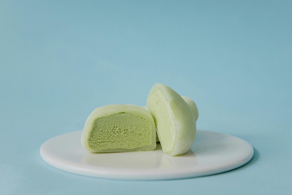 Creamy green tea mochi on a white plate against a pastel blue background.