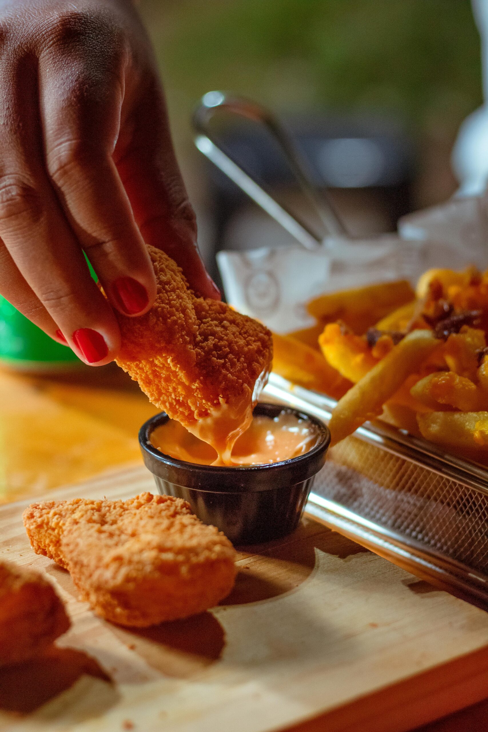 Close-up of chicken nuggets and fries being dipped in sauce. Unhealthy fast food snack.